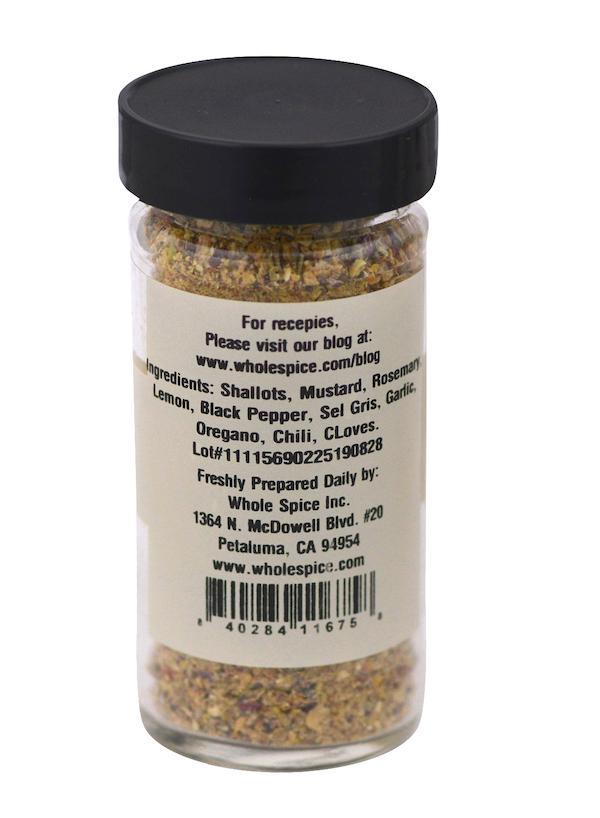 A clear spice jar with a black lid labeled "Roast Lamb Rub" by Whole Spice Inc. lists rosemary, mustard, lemon, and chili—ideal for roast lamb or kebabs. The label also includes company and contact details.