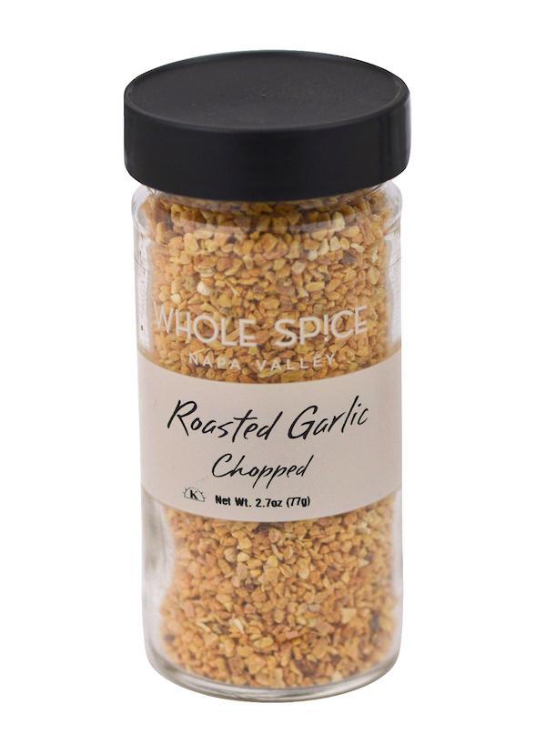 A glass jar with a black lid contains Garlic Roasted Chopped by Whole Spice Inc., net wt. 2.7oz (77g)—perfect for Mediterranean dishes.