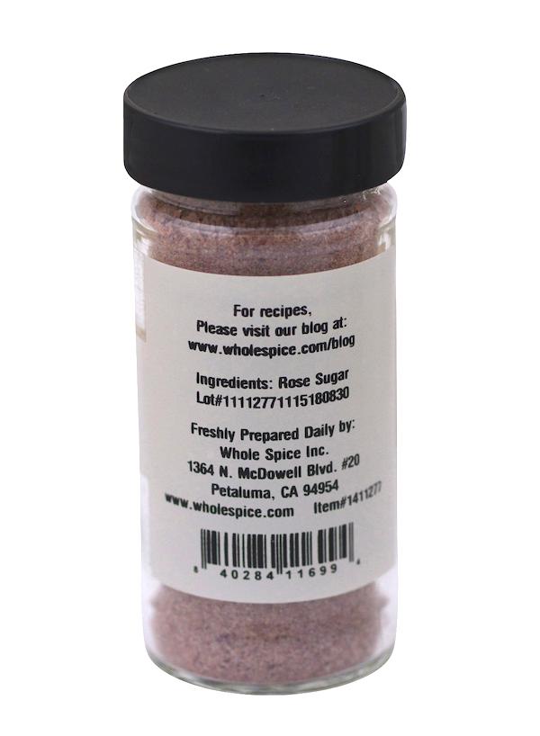 A clear spice jar with a black lid, labeled on the back with Rose Sugar by Whole Spice Inc., includes gourmet rose sugar info, supplier’s Petaluma, CA address, a barcode, and a website for recipes.