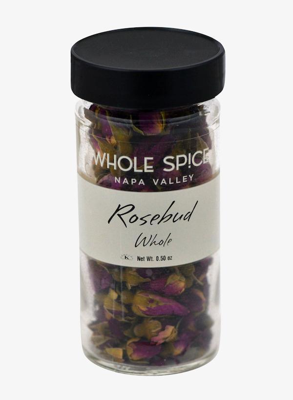 A clear glass jar with a black lid containing whole dried rosebuds from Whole Spice Inc.—perfect for tea or baking recipes. The label reads Rosebuds.