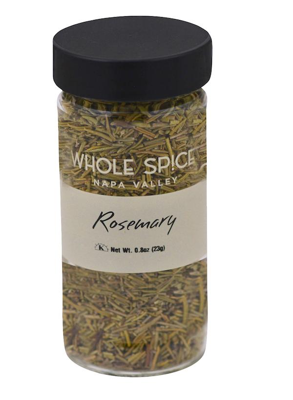 A clear glass jar with a black lid contains dried rosemary from Whole Spice Inc. The label reads "Rosemary" and notes a net weight of 0.8oz (23g).
