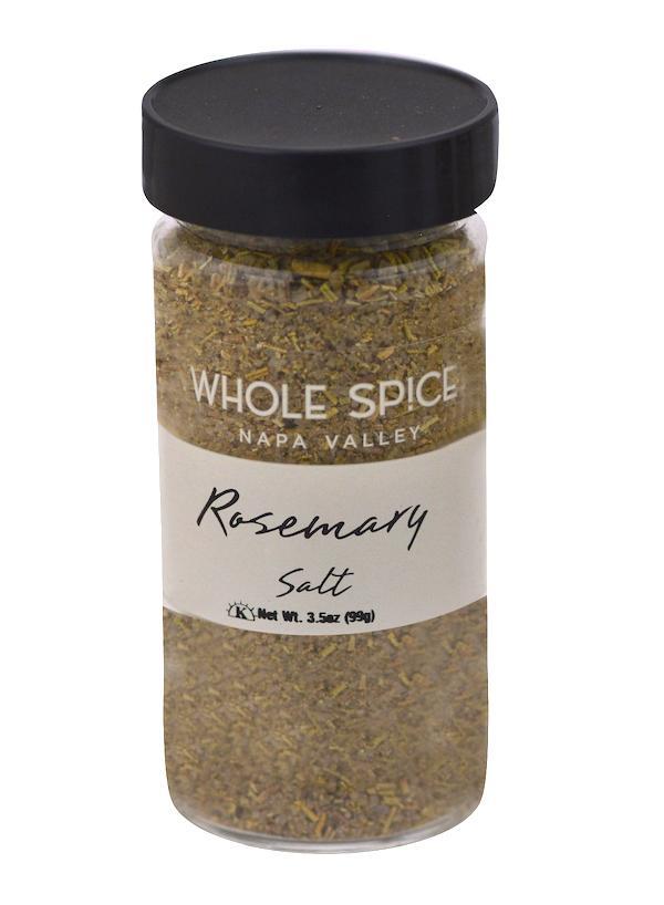A clear spice jar with a black lid labeled Whole Spice Inc. Rosemary Salt contains a coarse greenish-brown rosemary sea salt blend. Net weight: 3.5 oz (99g).