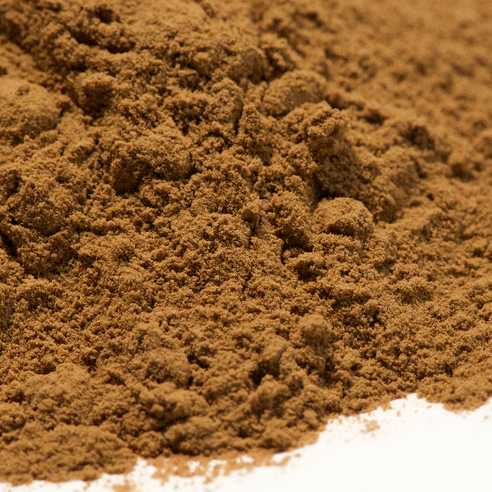 A close-up of finely ground brown Tamarind Instant powder by Whole Spice Inc., spread on a white surface—ideal for adding authentic Southeast Asian flavor to your dishes as a tamarind ingredient.