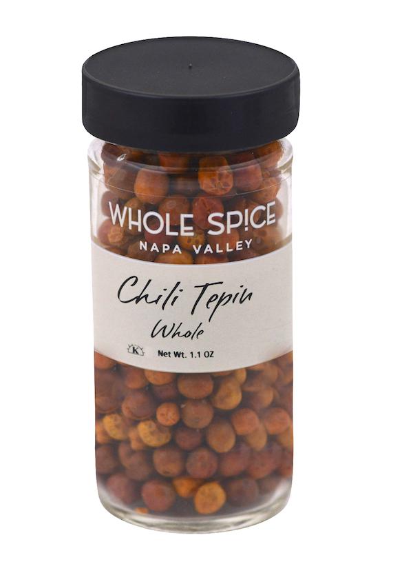 A clear glass jar with a black lid, filled with fiery whole Tepin Chili peppers. The label reads Whole Spice Inc., Tepin Chili Whole, Net Wt. 1.1 oz.