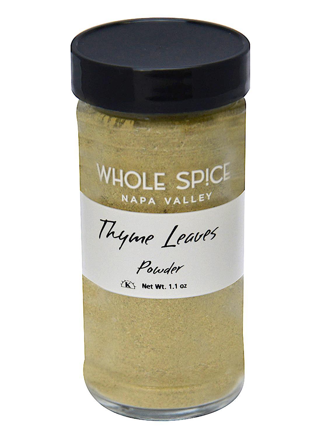 A clear glass jar with a black lid, labeled Whole Spice Inc. Thyme Powder, Net Wt. 1.1 oz, contains light greenish-brown thyme powder—a versatile herb ideal for seasoning various dishes.
