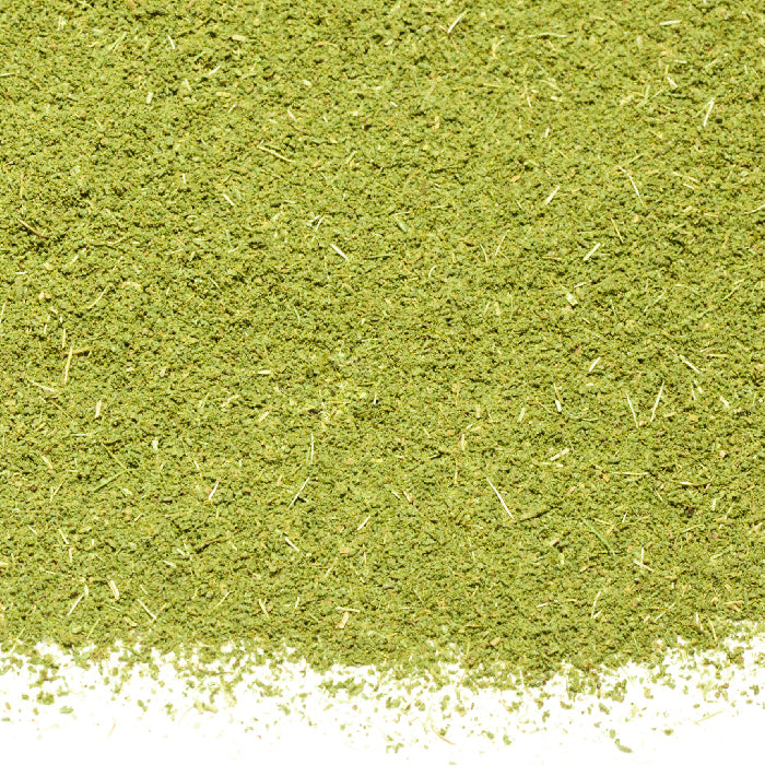 A close-up of Whole Spice Inc. Thyme Powder Organic shows green, finely ground powder with small particles on a white background. The dry, slightly uneven texture highlights this versatile, multi-purpose herb.