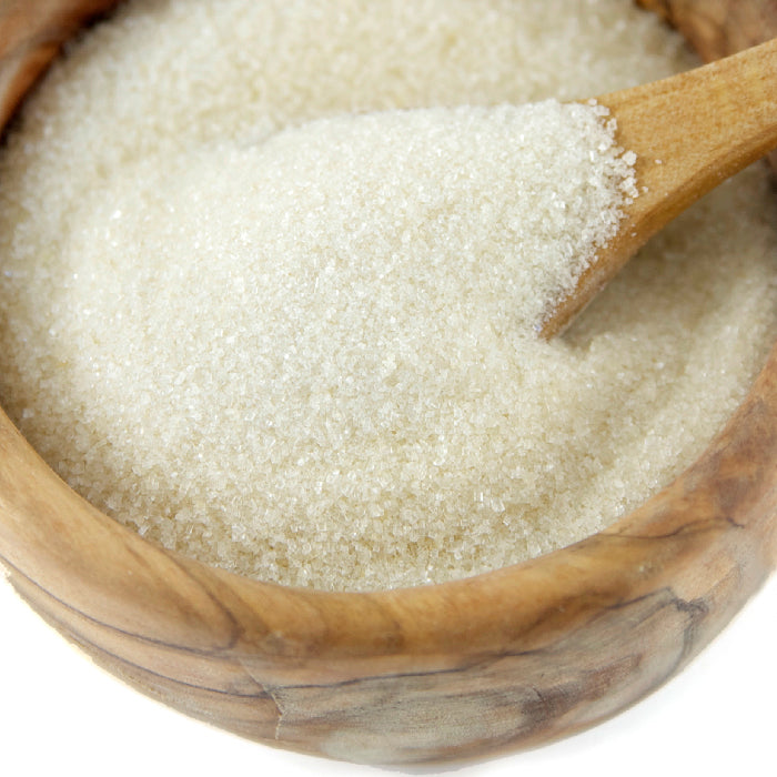 A wooden bowl holds coarse, light brown Whole Spice Inc. Turbinado Sugar, with a wooden spoon scooping some of the unrefined sugar.