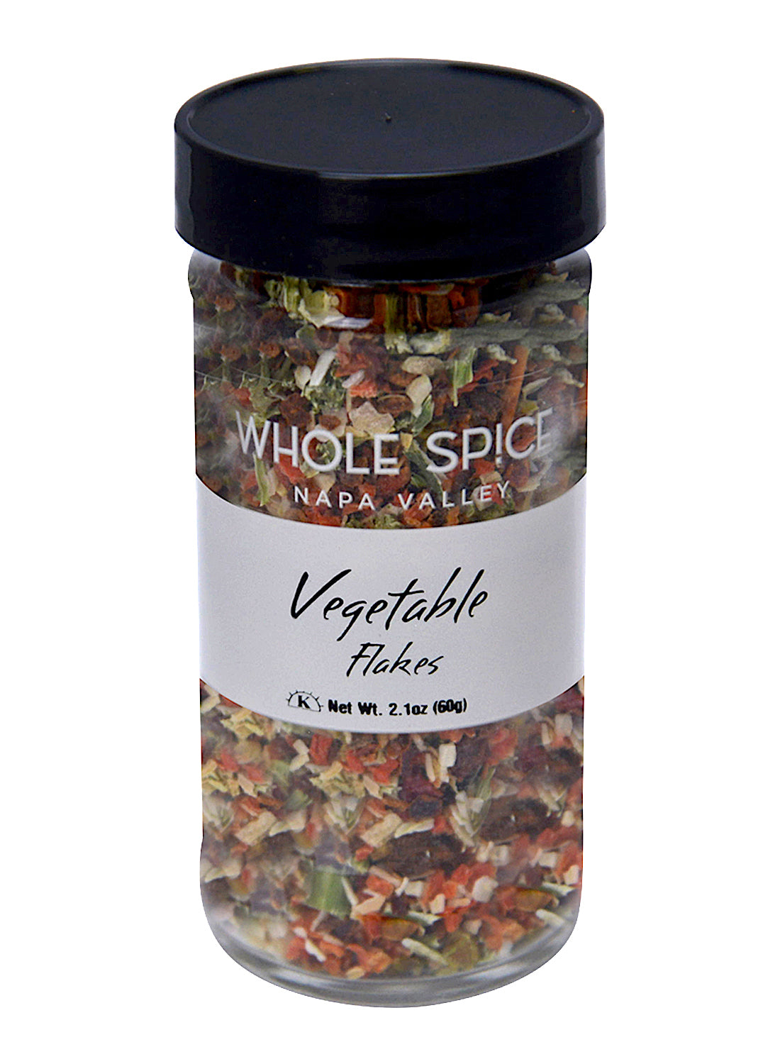 A clear glass jar with a black lid holds colorful Vegetable Flakes by Whole Spice Inc., ideal for soups or salad dressings. The label states Net Wt. 2.1oz (60g).