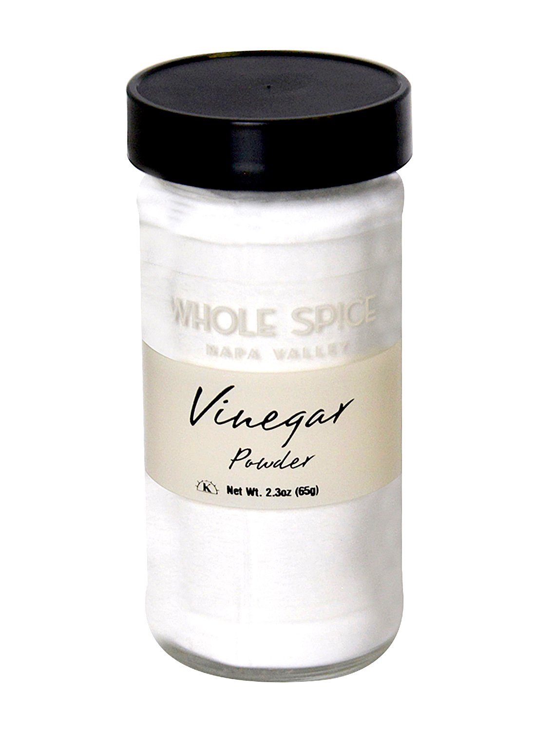 A clear glass jar with a black lid contains Vinegar Powder by Whole Spice Inc., Net Wt. 2.3oz (65g). The label displays the product name and brand, and the background is plain white.